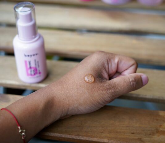 2030세대, 건강한 피부는 ‘장벽’부터…스킨케어도 건강 트렌드 a woman's hand holding a bottle of sunscreen on a wooden bench
