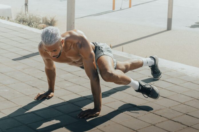 Photo by Salah Regouane a man doing push ups on a brick sidewalk