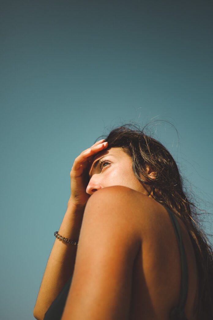 Photo by Adam Neumann woman in silver bracelet covering her face with her hand