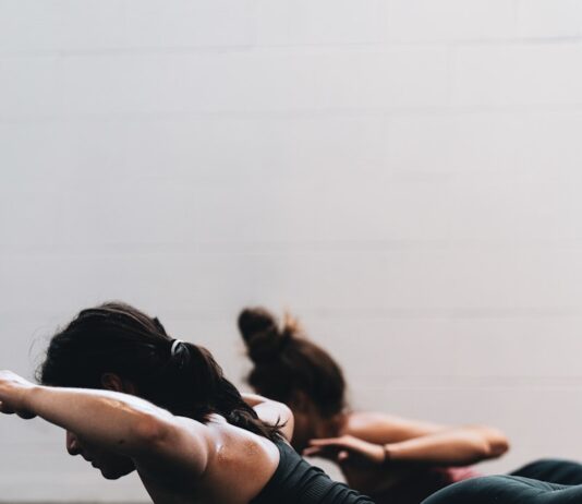 필라테스, 몸과 마음의 균형을 잡아주는 현대인의 필수 운동 woman in black tank top and black leggings lying on black floor
