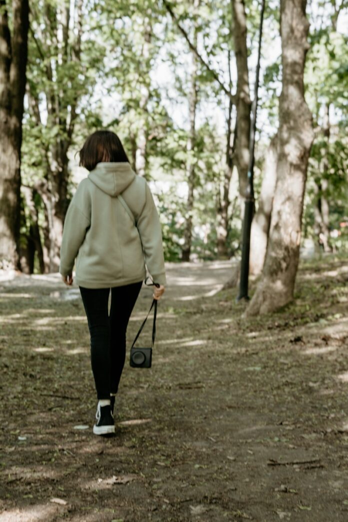Photo by Hanna Balan woman in green coat walking on pathway during daytime