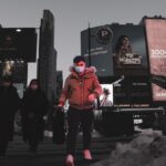 ‘웰빙의 비결, 꾸준한 걷기 생활’… 일상 속 걷기 습관으로 건강 챙기기 a woman wearing a face mask walking down a street