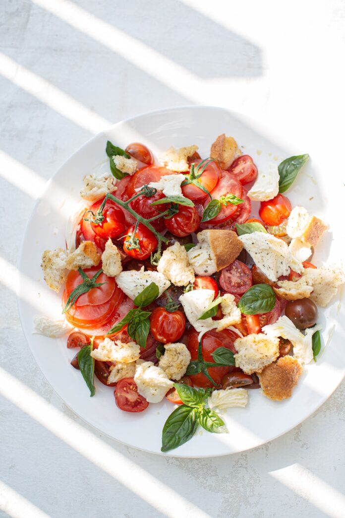 sliced tomato and green leaf vegetable on white ceramic plate