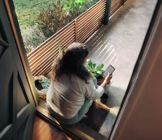만성피로, 일상을 바꾸는 작지만 강력한 루틴의 힘 Woman sitting on balcony with smartphone
