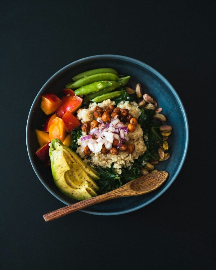 Photo by Sonny Mauricio a blue bowl filled with vegetables and a wooden spoon
